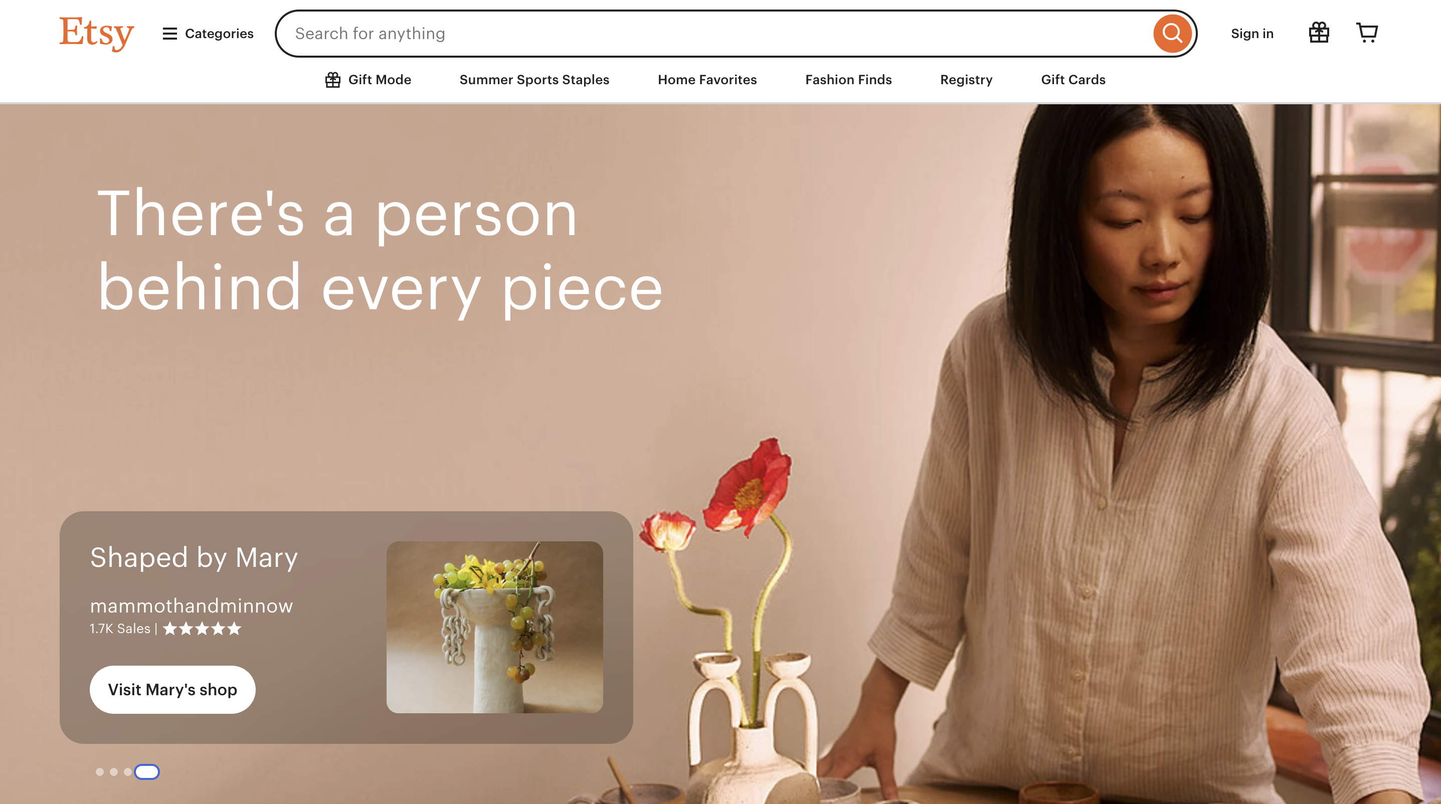 Etsy homepage: Woman arranging flowers by handmade pottery. Text: 'There's a person behind every piece'. 