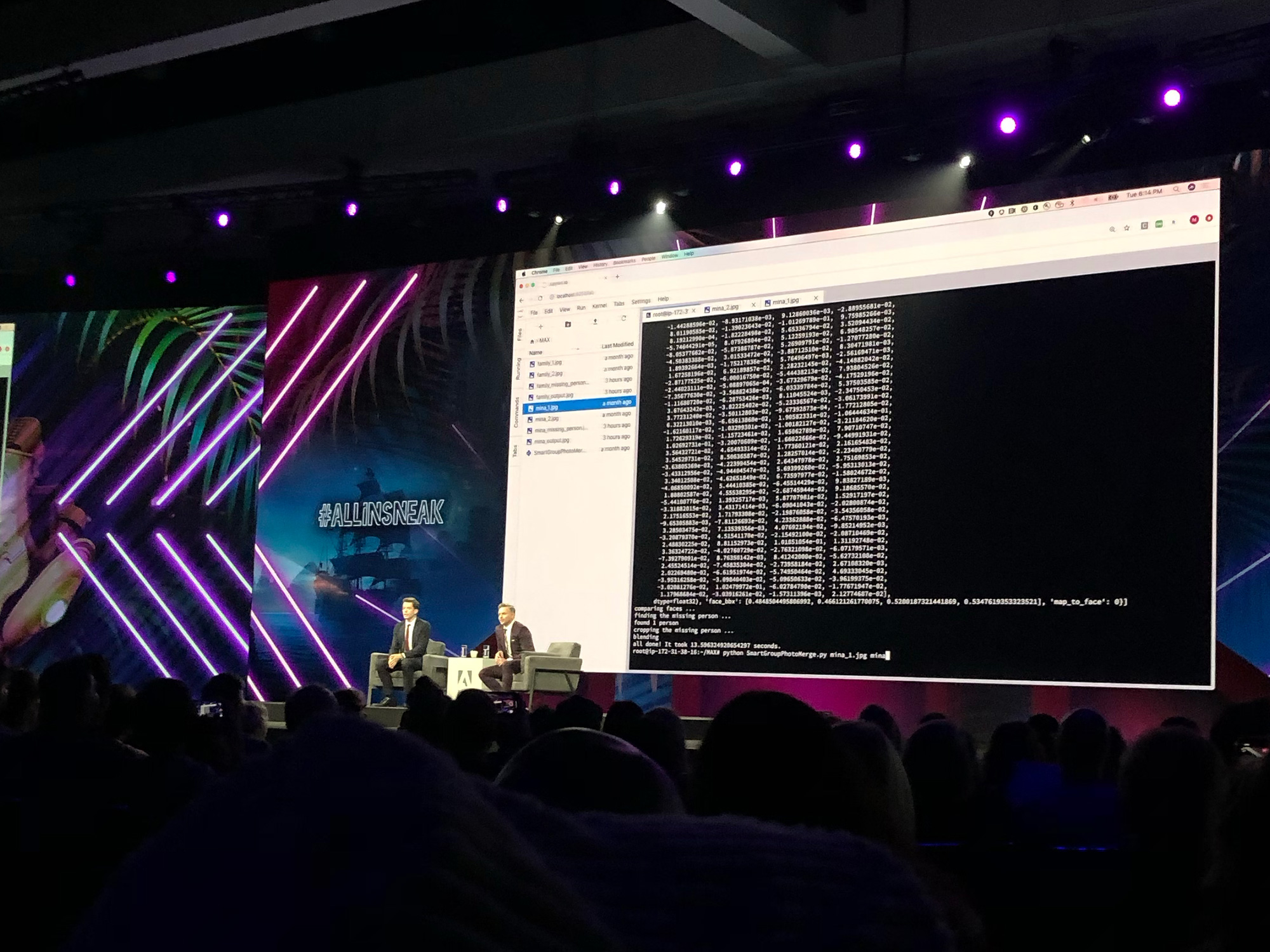 Tech conference stage showing two speakers and a large code display screen with purple lighting